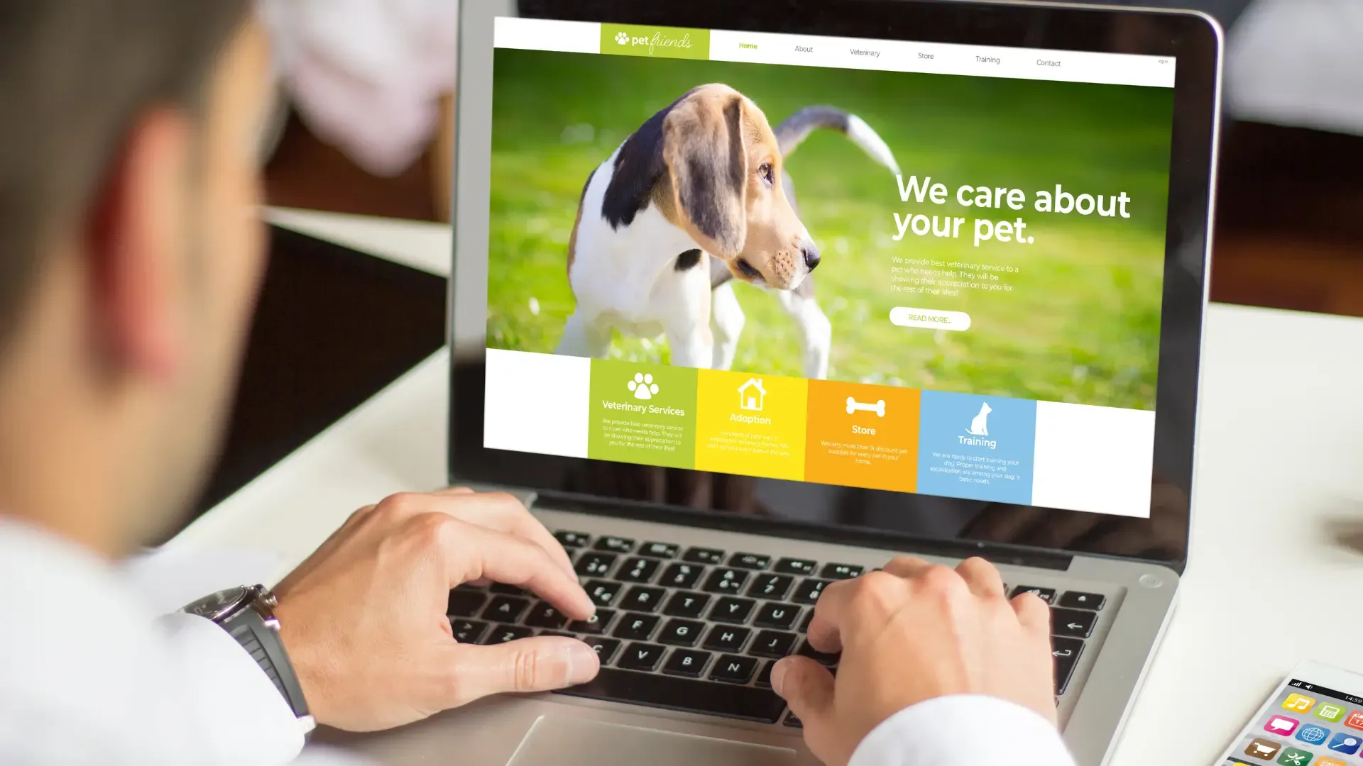A man types on a laptop, with a website about dogs on the screen